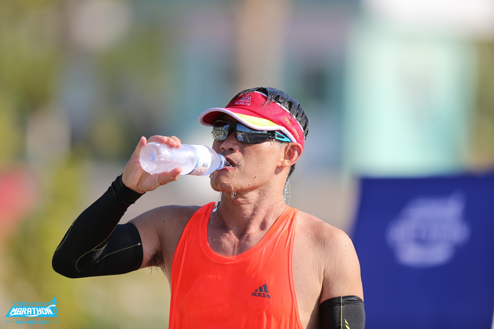 Một vận động viên tiếp nước trên đường chạy VM Quy Nhơn 2020. Ảnh: VnExpress Marathon.