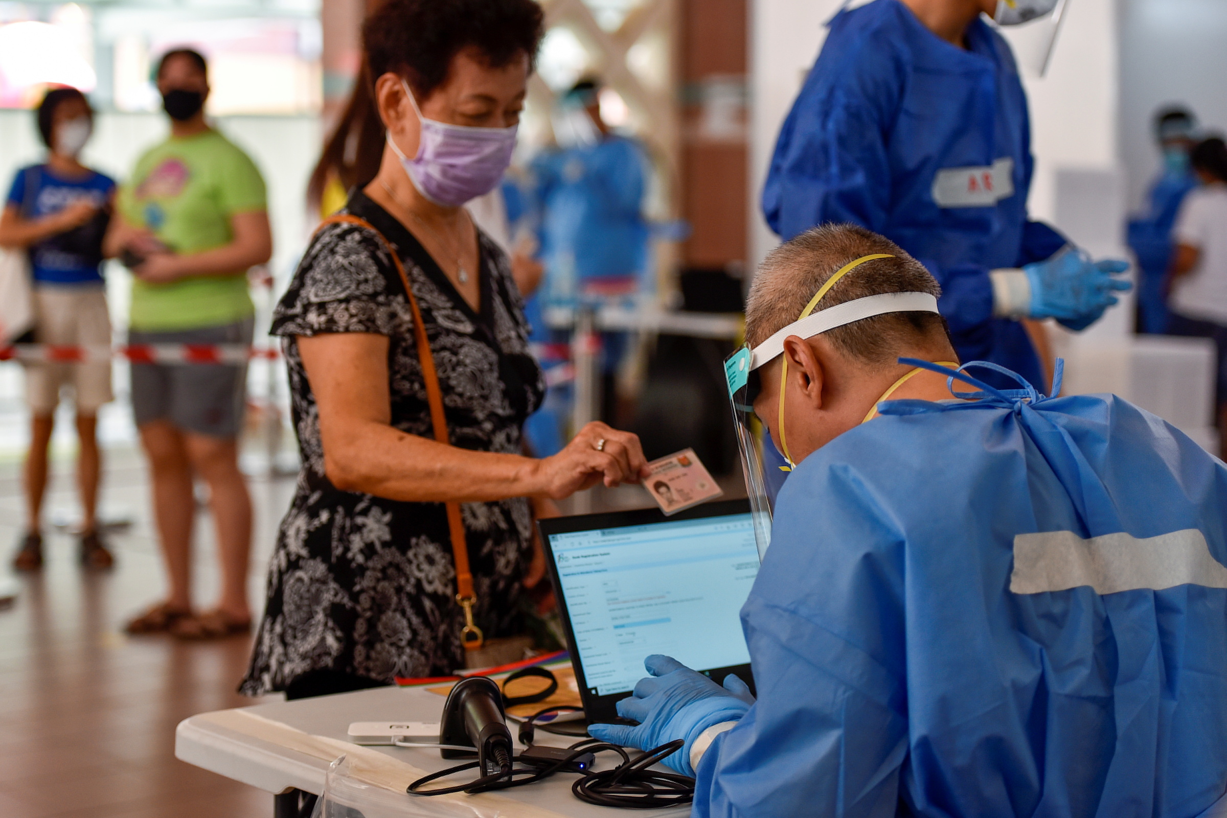 Nhân viên y tế Singapore kiểm tra thông tin của một người tới xét nghiệm nCoV ngày 16/6. Ảnh: Reuters